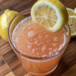 Glass of pink salt water with lemon on marble